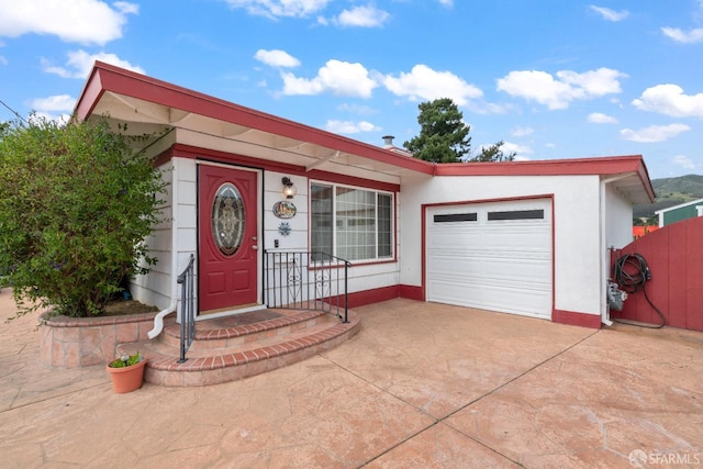 ranch-style house with concrete driveway, fence, and an attached garage