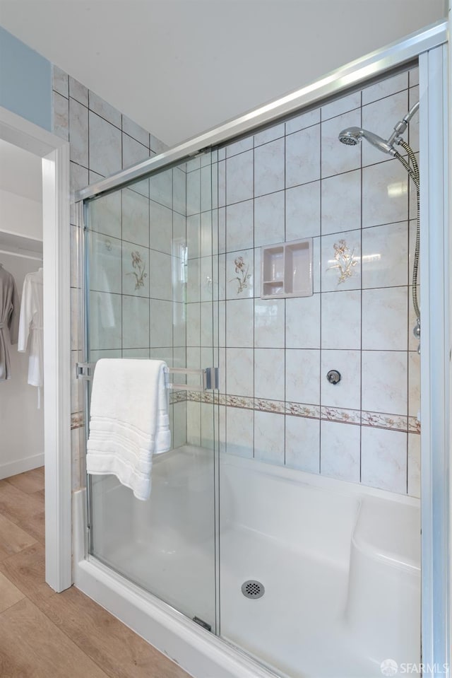 full bath featuring a shower stall and wood finished floors