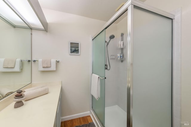 full bathroom featuring vanity, wood finished floors, a stall shower, and baseboards