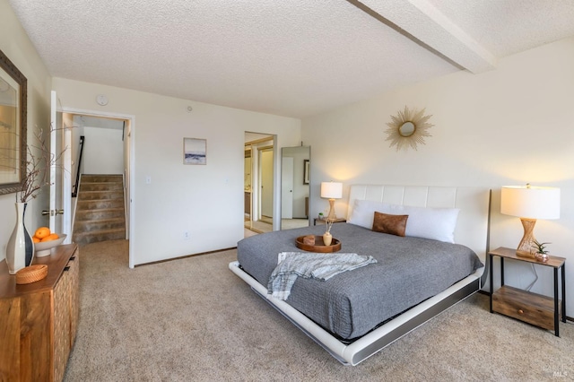 carpeted bedroom featuring beamed ceiling and a textured ceiling