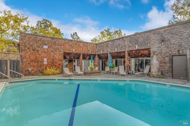 community pool with a patio area and fence