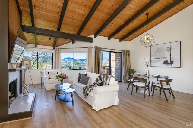 living area with a fireplace with raised hearth, wood ceiling, beam ceiling, light wood-style floors, and a mountain view