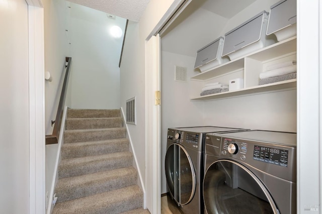 washroom with washer and dryer, visible vents, a textured ceiling, and laundry area