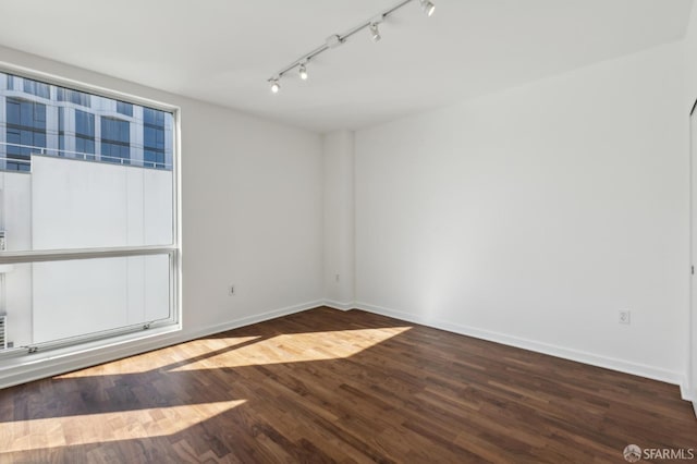 unfurnished room featuring track lighting, baseboards, and wood finished floors