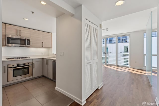 kitchen with stainless steel appliances, baseboards, light countertops, recessed lighting, and light brown cabinets