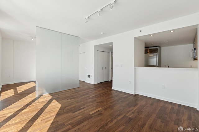 unfurnished room with wood finished floors, track lighting, baseboards, and recessed lighting
