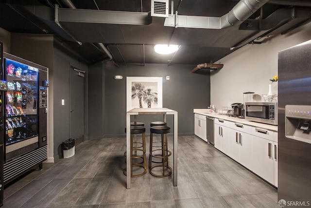 kitchen with stainless steel appliances, white cabinetry, light countertops, a sink, and baseboards