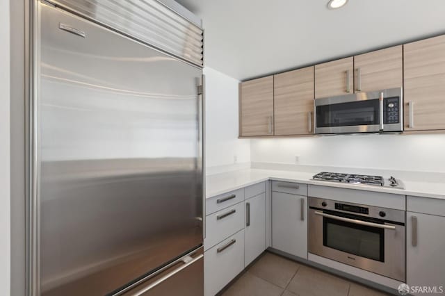 kitchen featuring stainless steel appliances, light tile patterned floors, light countertops, and gray cabinets