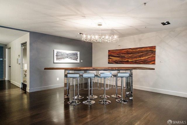 bar area with wood finished floors, a chandelier, and baseboards