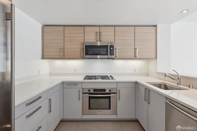 kitchen featuring stainless steel appliances, a sink, light countertops, recessed lighting, and light tile patterned floors