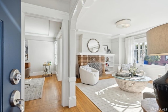 living area with crown molding, a fireplace, and hardwood / wood-style floors