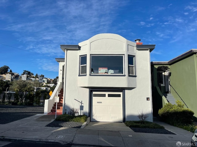 view of front of house featuring stairway, an attached garage, and stucco siding