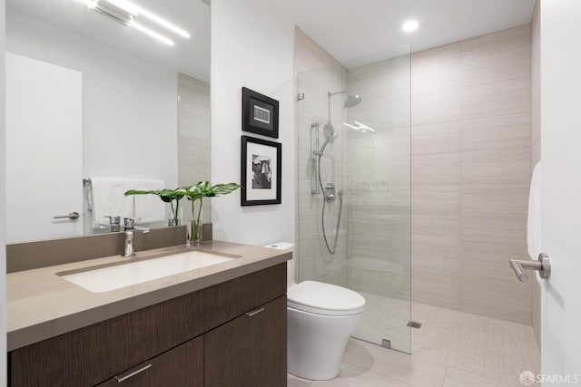 bathroom with a tile shower, tile patterned flooring, vanity, and toilet