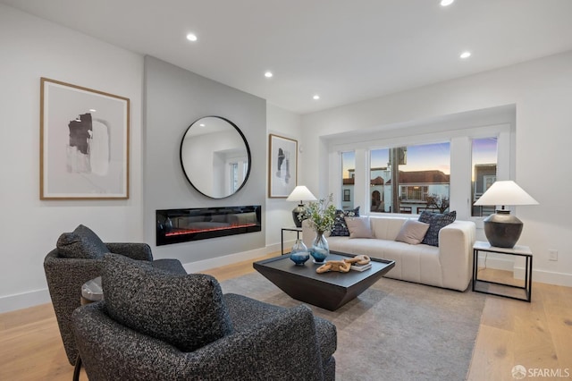 living area featuring recessed lighting, baseboards, wood finished floors, and a glass covered fireplace