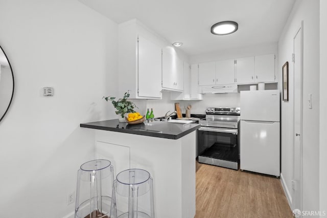 kitchen with white cabinets, white refrigerator, kitchen peninsula, stainless steel electric range oven, and light hardwood / wood-style flooring