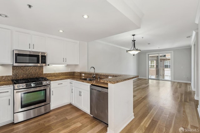 kitchen with kitchen peninsula, white cabinetry, sink, and appliances with stainless steel finishes