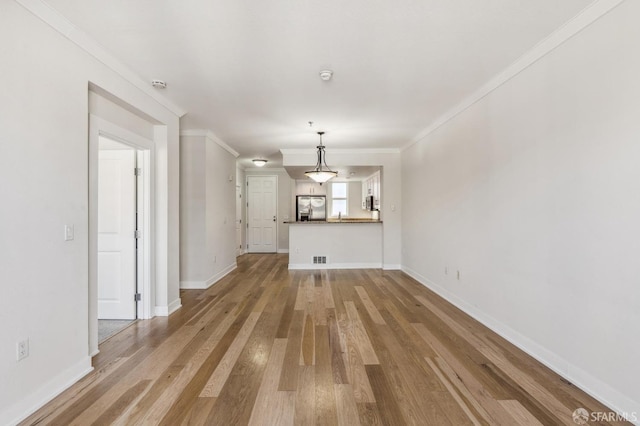 unfurnished living room featuring hardwood / wood-style flooring and ornamental molding