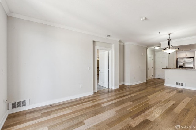 unfurnished living room featuring light wood-type flooring and crown molding