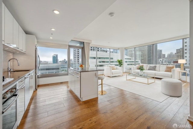 kitchen featuring white cabinets, a center island, appliances with stainless steel finishes, sink, and a breakfast bar area