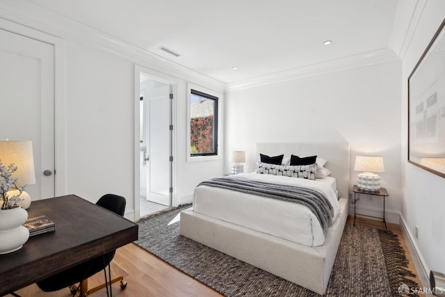 bedroom featuring light wood-type flooring, ornamental molding, and a desk