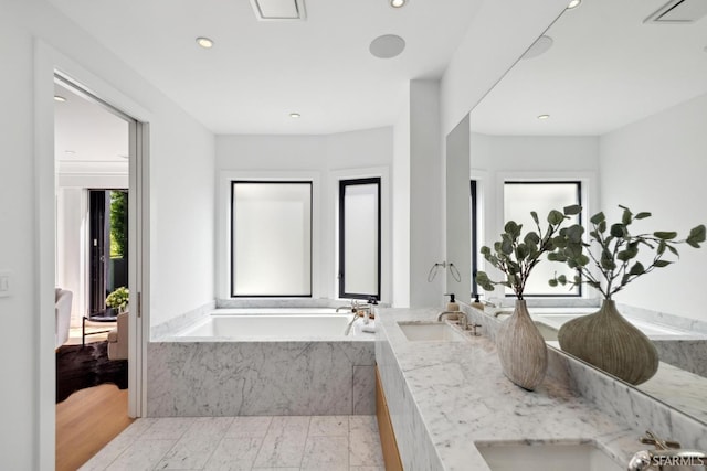 bathroom with a bath, double vanity, and recessed lighting