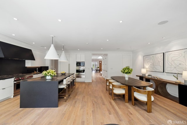 dining area with crown molding, light wood-style floors, and recessed lighting