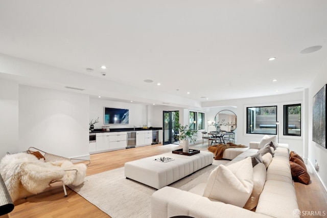 living room with light wood-type flooring, recessed lighting, and beverage cooler