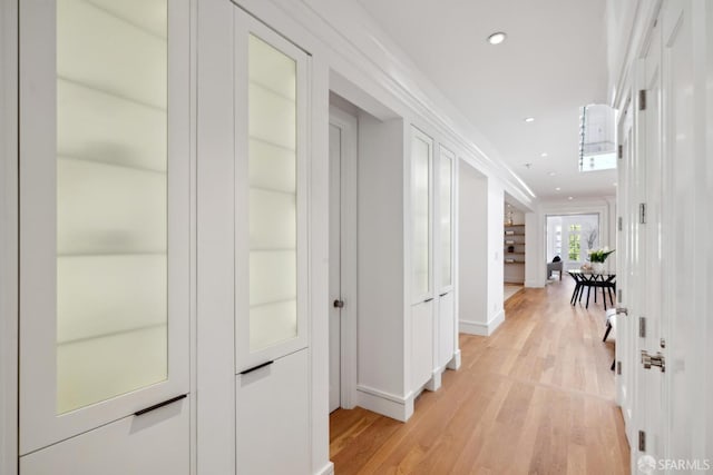 hallway featuring light wood-style floors, baseboards, and recessed lighting