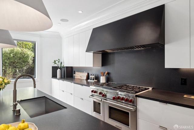 kitchen featuring range with two ovens, premium range hood, a sink, dark countertops, and ornamental molding