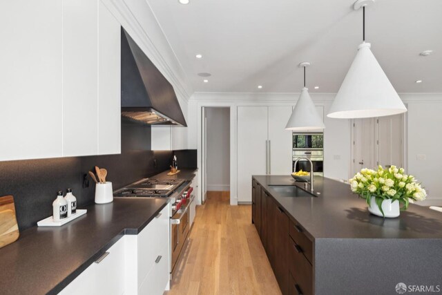 kitchen with a sink, stainless steel appliances, modern cabinets, dark countertops, and crown molding
