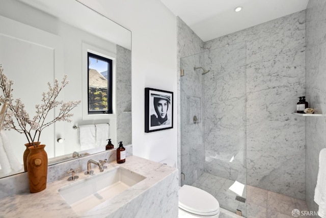 bathroom with toilet, a marble finish shower, and vanity
