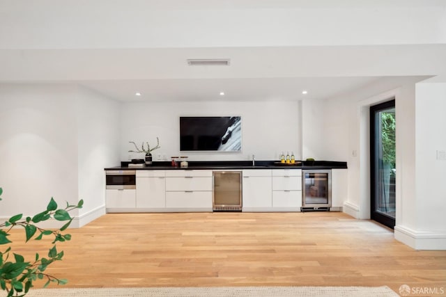 indoor wet bar featuring wine cooler, light wood finished floors, recessed lighting, and baseboards