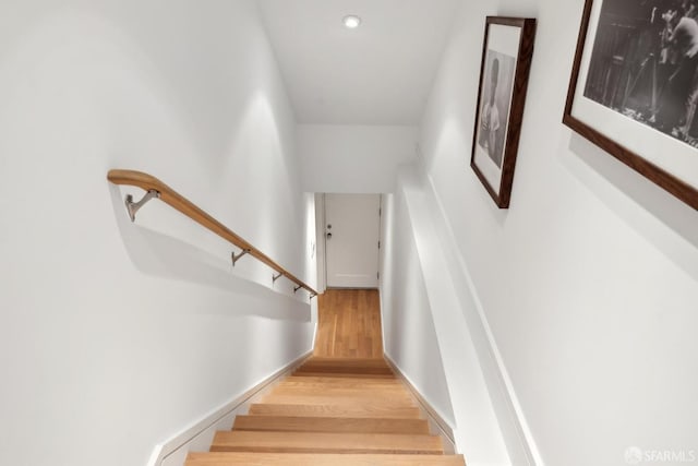 staircase featuring wood finished floors and baseboards