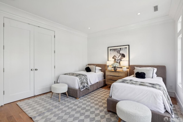 bedroom featuring light wood-type flooring, ornamental molding, a closet, and recessed lighting