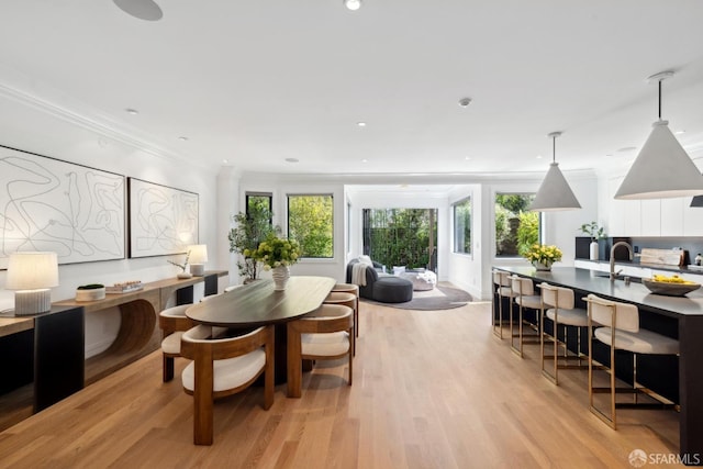 dining area with light wood finished floors, crown molding, and recessed lighting