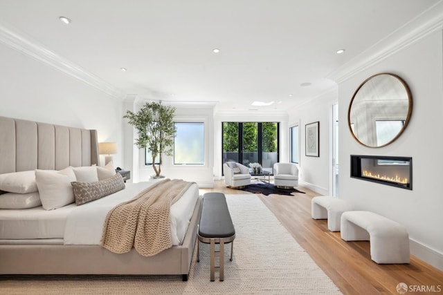 bedroom with crown molding, light wood-style flooring, a glass covered fireplace, baseboards, and recessed lighting