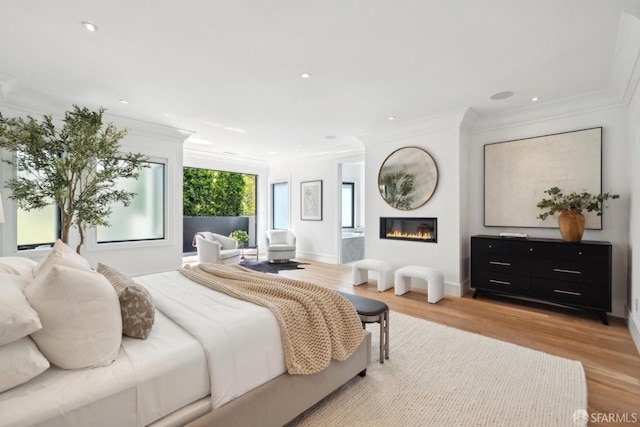 bedroom with ornamental molding, a glass covered fireplace, light wood-style floors, and recessed lighting