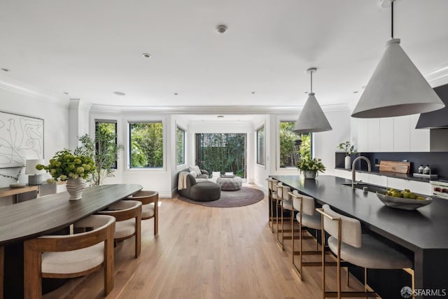 dining space with light wood-style floors and crown molding