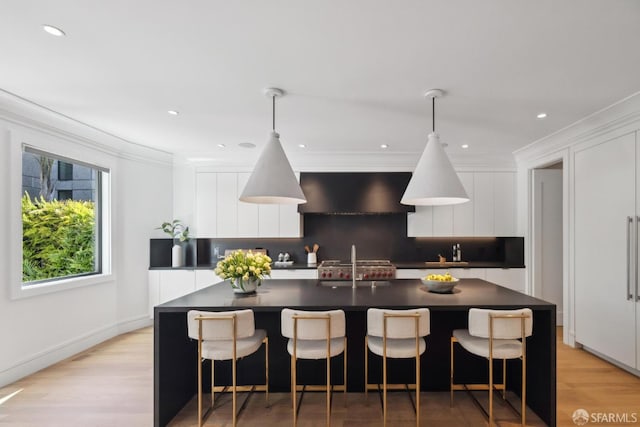 kitchen with dark countertops, modern cabinets, white cabinets, crown molding, and a spacious island