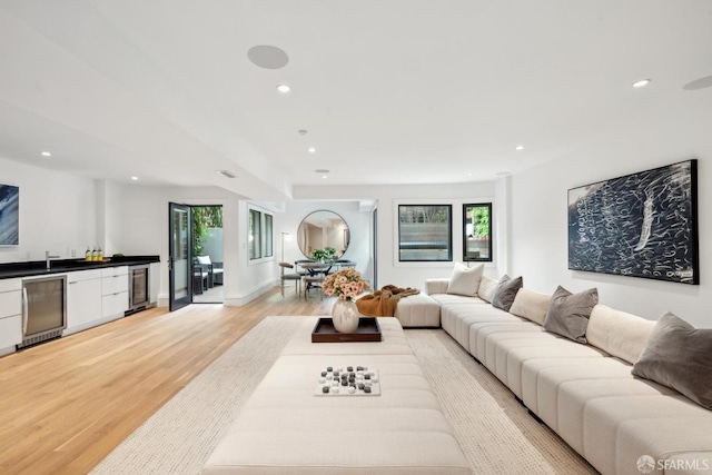 living room with wet bar, light wood-type flooring, recessed lighting, and wine cooler
