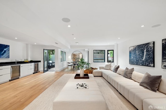 living room featuring light wood finished floors, wine cooler, plenty of natural light, bar, and recessed lighting