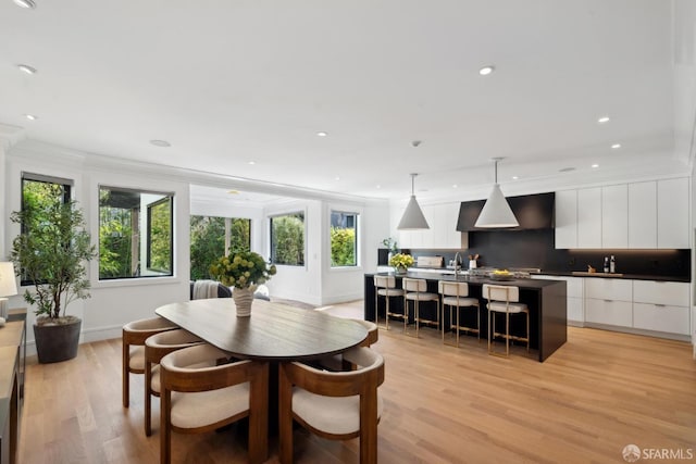 dining space with light wood-style floors, baseboards, crown molding, and recessed lighting