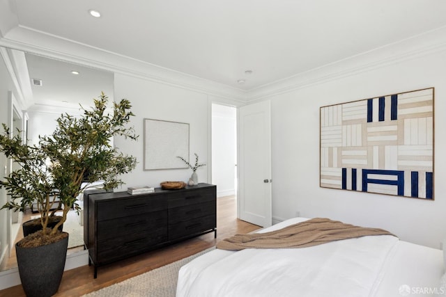 bedroom with wood finished floors, crown molding, and recessed lighting