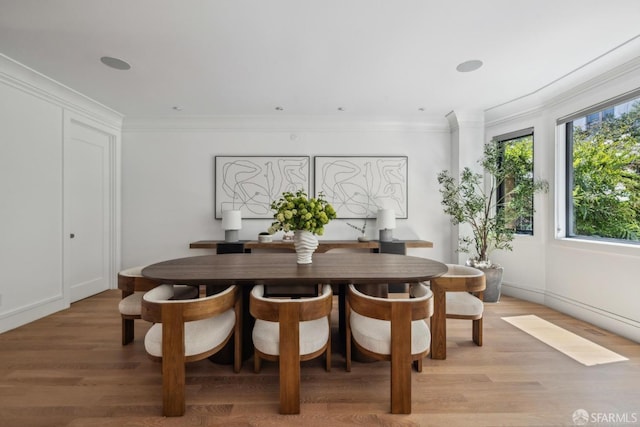 dining space featuring light wood finished floors and crown molding
