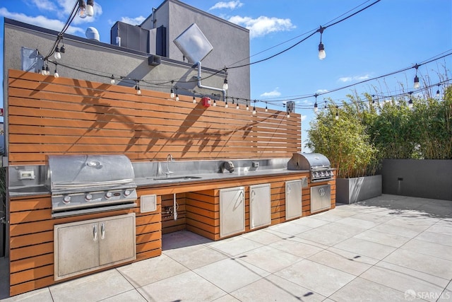 view of patio featuring exterior kitchen, a grill, a sink, and fence