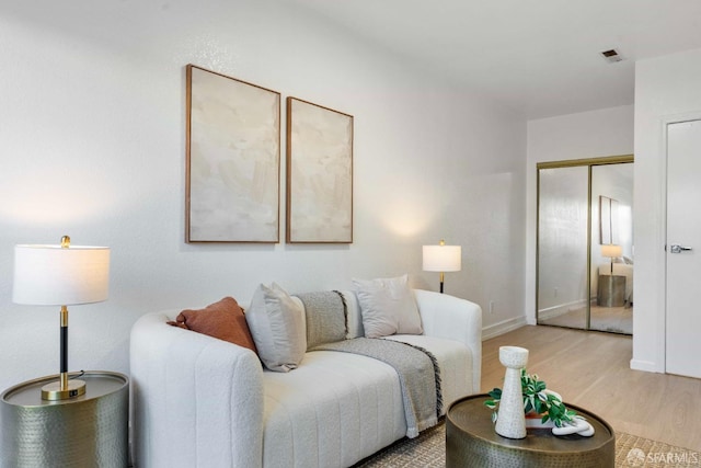 living area featuring light wood-style floors, baseboards, and visible vents