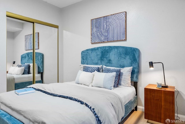 bedroom with a closet, light wood-style flooring, and baseboards