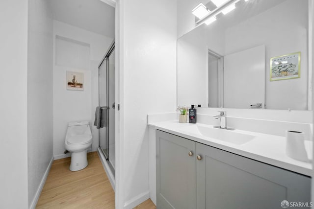 bathroom featuring a stall shower, vanity, toilet, and wood finished floors