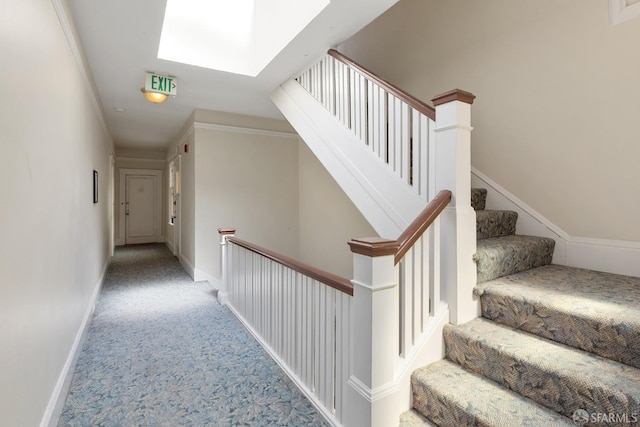 staircase with a skylight, baseboards, and carpet flooring