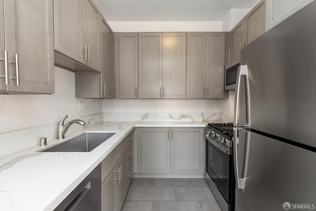 kitchen featuring stainless steel appliances, light stone counters, a sink, and light tile patterned floors